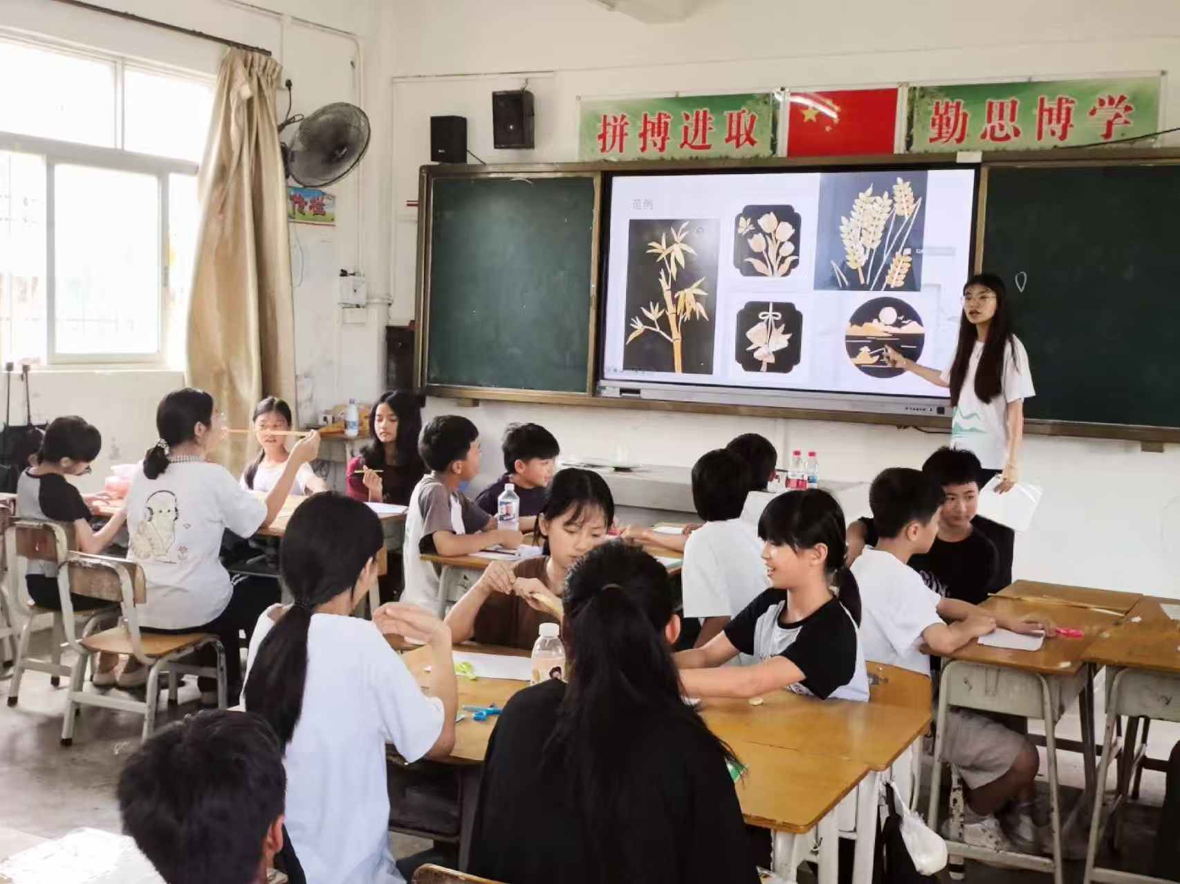 图为岭陆前行突击队队员在给学生介绍碣石镇非遗麦秆画（黄河舟 摄）