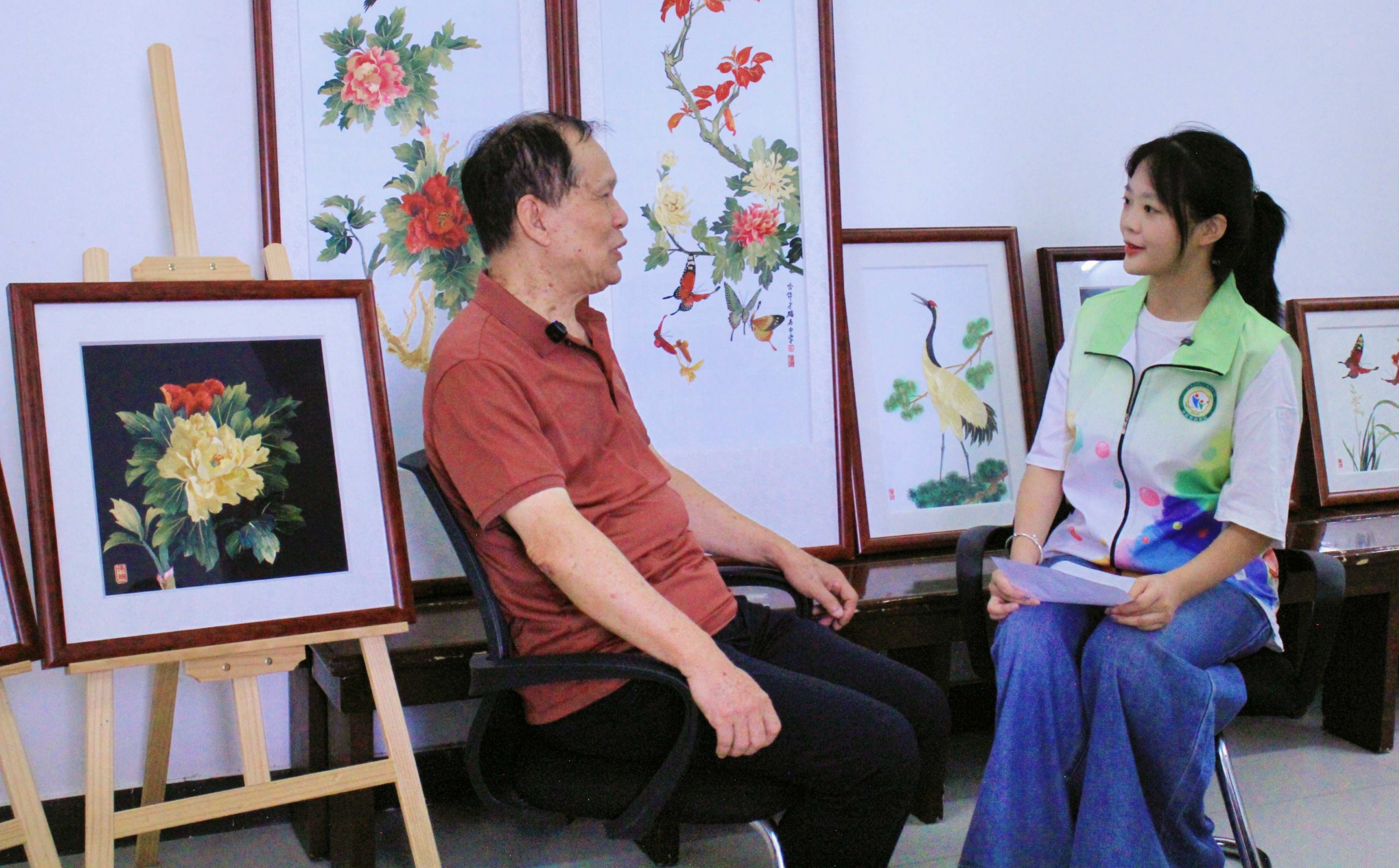 图为匠人林锡安向队员介绍麦秆画由来.jpg