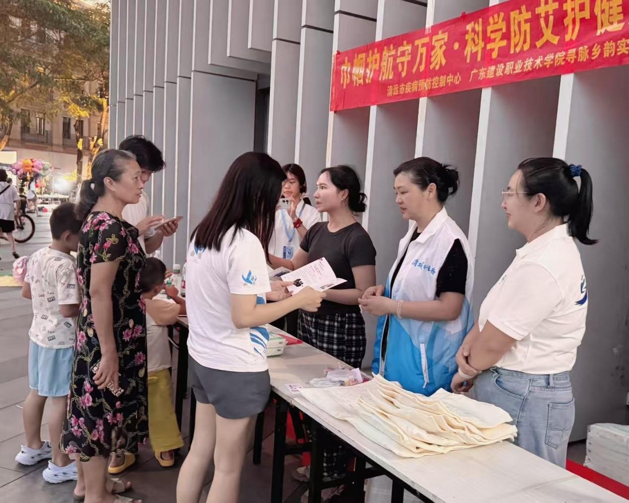 图六 社区妇联主席莅临防艾活动宣传现场协助实践队员开展宣讲活动（李健涛 摄） ... ...