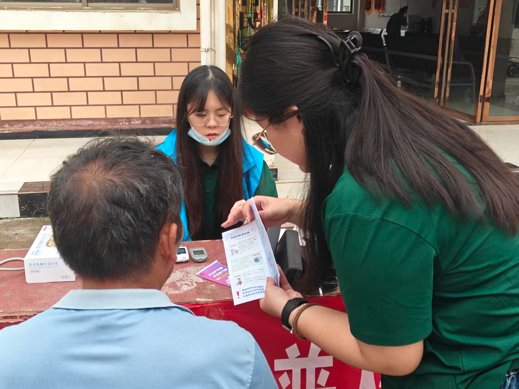 图为实践团成员在展良村向当地居民科普慢性病和反诈骗知识.jpg